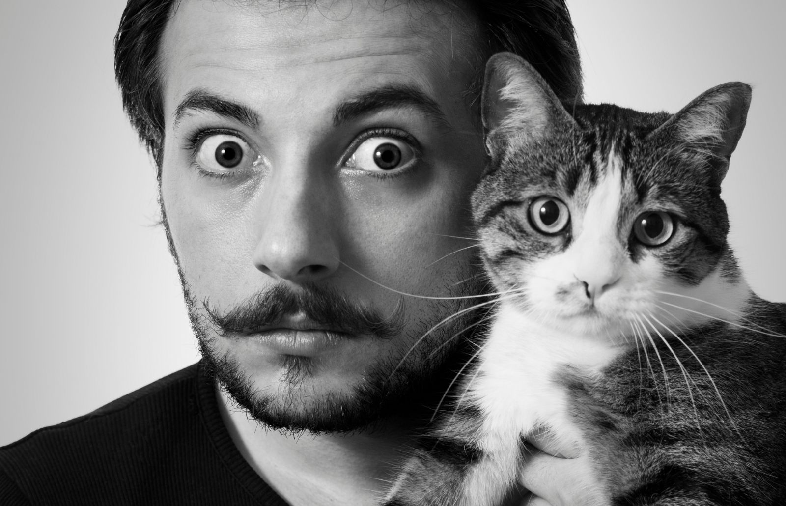 Foto in bianco e nero di Salvador Dal che tiene nelle mani un gatto vicino al suo viso.