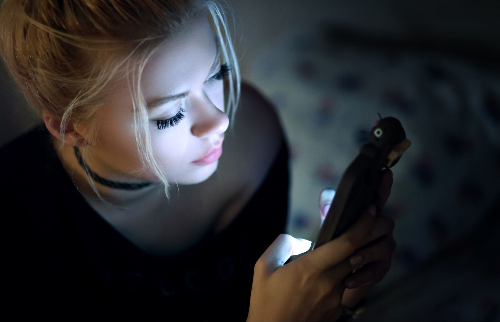 Ragazza giovane con lo smartphone in mano. la luce intensa dello schermo è riflessa sul viso.